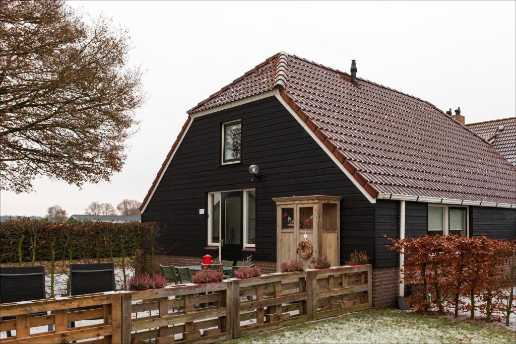 a black house with a wooden fence in front of it at Villa Grace in Dalfsen
