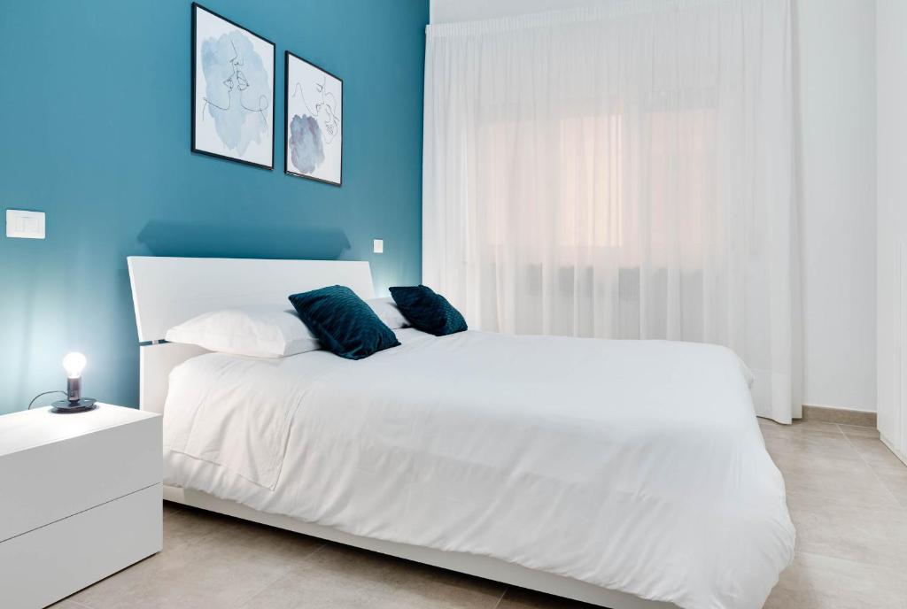 a bedroom with a white bed and a blue wall at Jòia Holiday Home in Crotone
