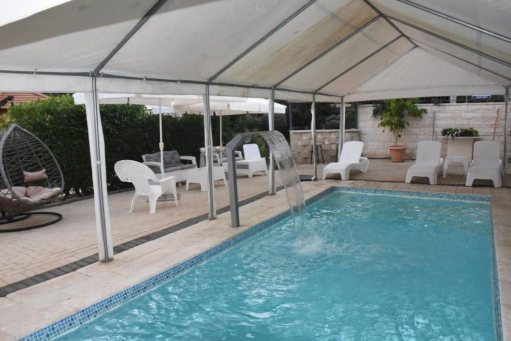 einen Pool mit einem weißen Sonnenschirm und Stühlen sowie einem Pool in der Unterkunft Sounds Suite for families in Migdal