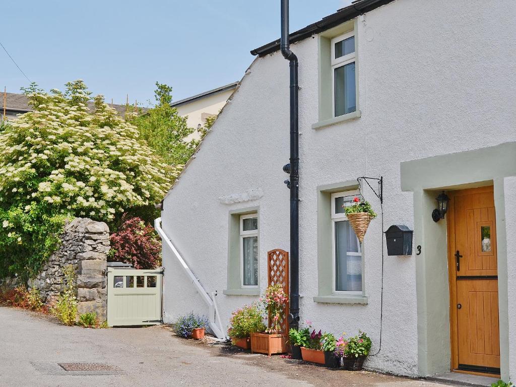 una casa blanca con una puerta y un árbol florido en Jackdaw Cottage, en Baycliff