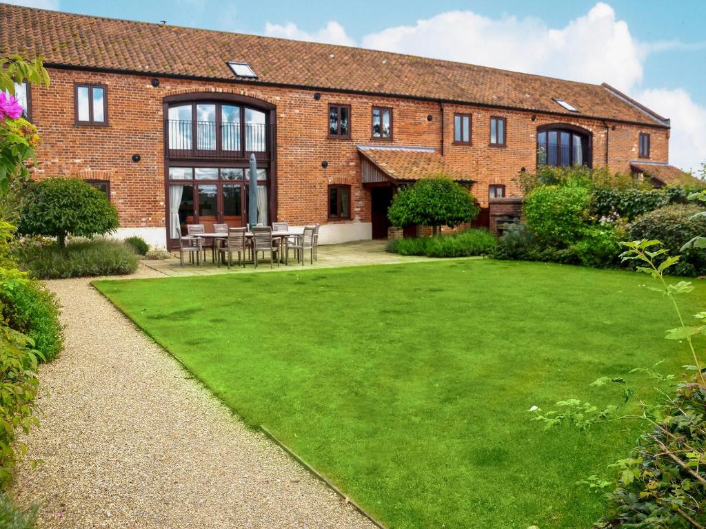 a brick building with a lawn in front of it at Kestrel Barn - Cul in Sculthorpe