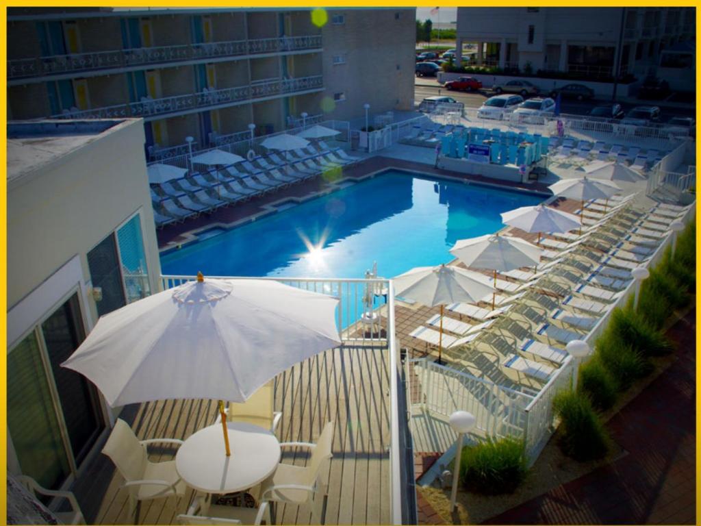 - une piscine avec des chaises blanches et un parasol dans l'établissement The Jolly Roger Motel, à Wildwood Crest