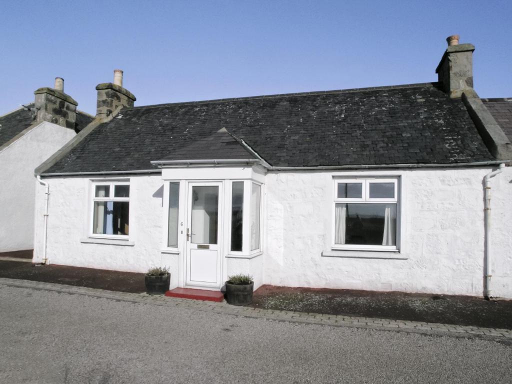 a white house with a black roof at Middledrift Cottage in Brora