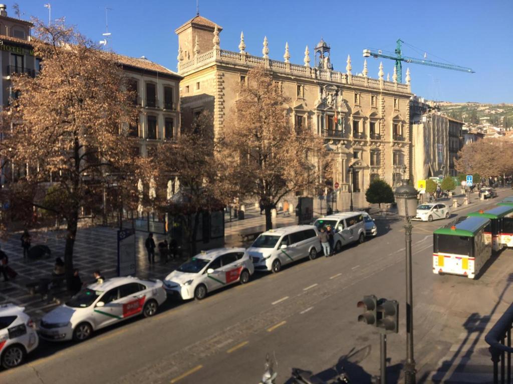 una fila de autos estacionados frente a un edificio en Plaza Nueva's House "El Consul", en Granada