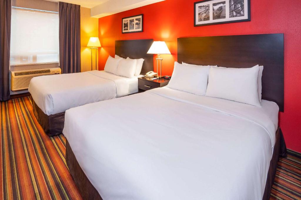 2 bedden in een hotelkamer met rode muren bij Comfort Hotel & Suites in Peterborough