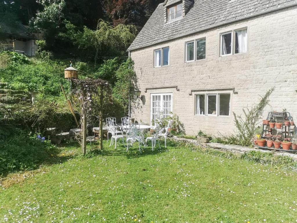 a garden with a table and chairs in front of a house at Violet Cottage in Dudbridge