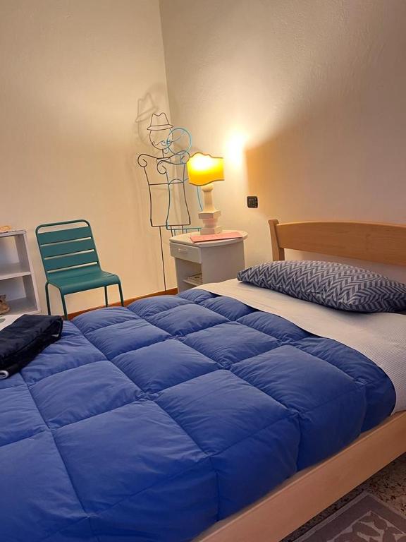 sypialnia z niebieskim łóżkiem i zielonym krzesłem w obiekcie B&B Camelia w mieście Città di Castello