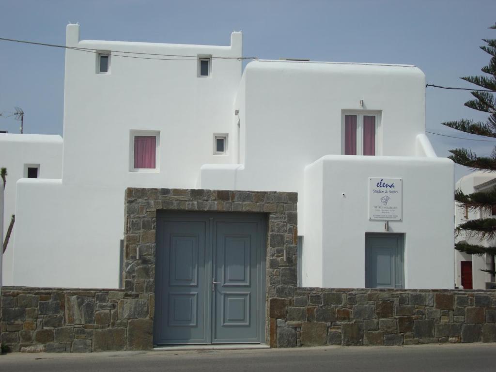 un edificio bianco con una porta blu davanti di Elena Studios & Suites a Ornos