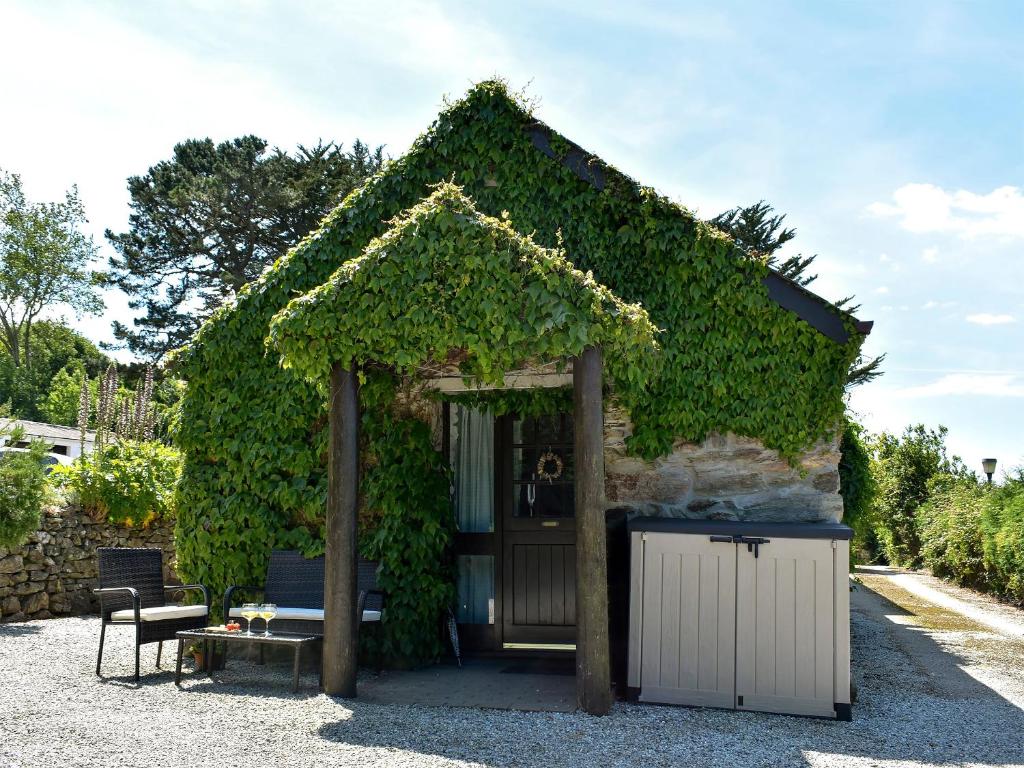 a small building covered in ivy with a door at Babes Cottage - 27592 in Perranzabuloe