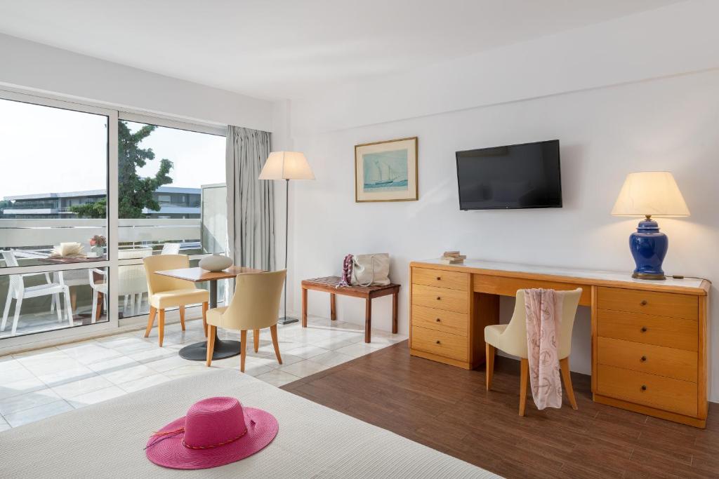 un soggiorno con una camera con tavolo e TV di Dionysos Hotel a Ixiá