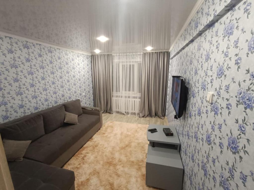 a living room with a couch and a tv at Lux Home на Амурской in Ustʼ-Kamenogorsk
