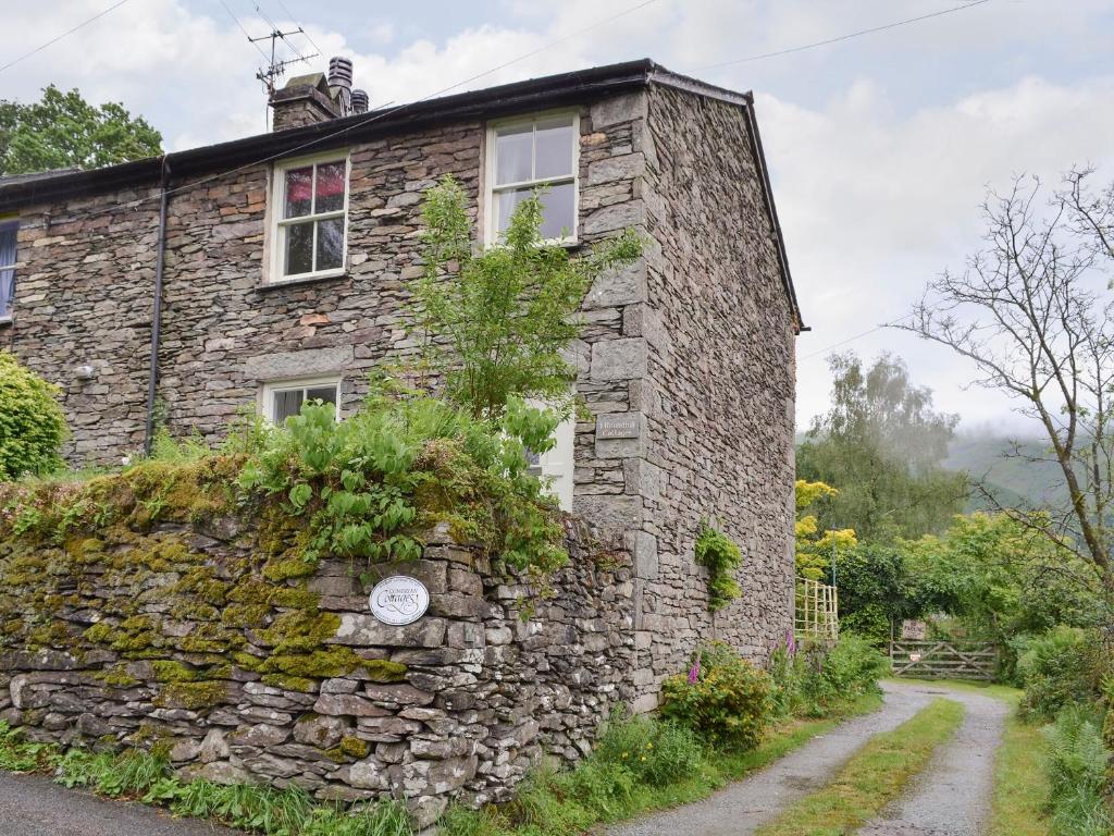 an old stone house with a stone wall at Roundhill Cottages 1 in Grasmere