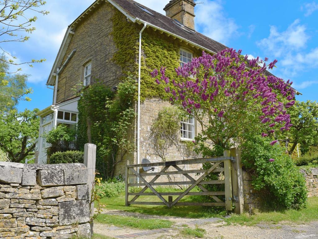 EnstoneにあるJubilee Cottageの門と紫の花々が咲く古い石造りの家