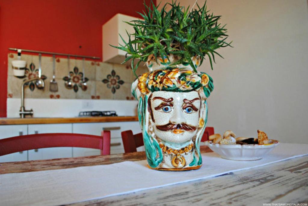 un jarrón con una cara en una mesa con una planta en Dimore del Valentino, en Sampieri