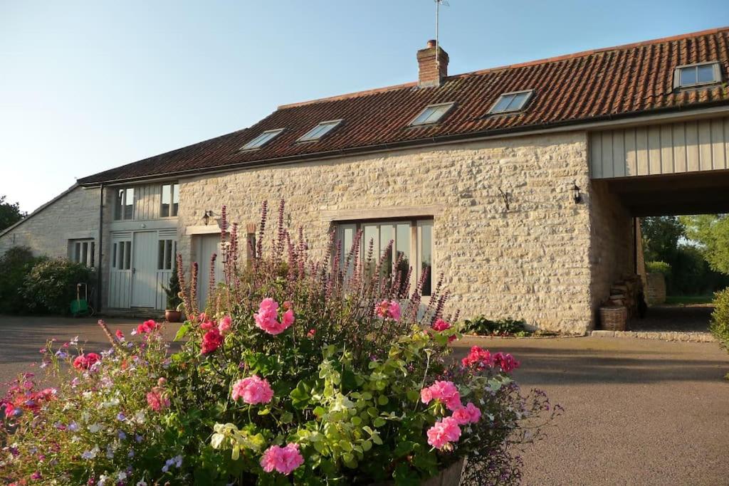 Baltonsborough的住宿－Brook Cottage，前面有鲜花的砖砌建筑