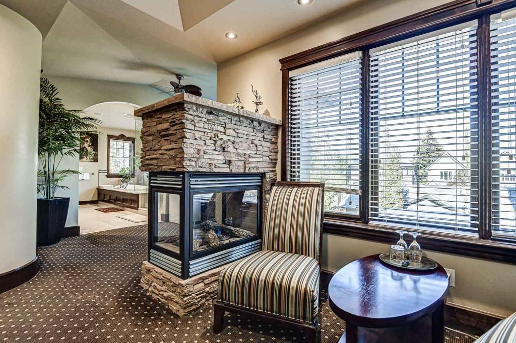a living room with a fireplace and a chair and a table at Westmount River Inn in Calgary