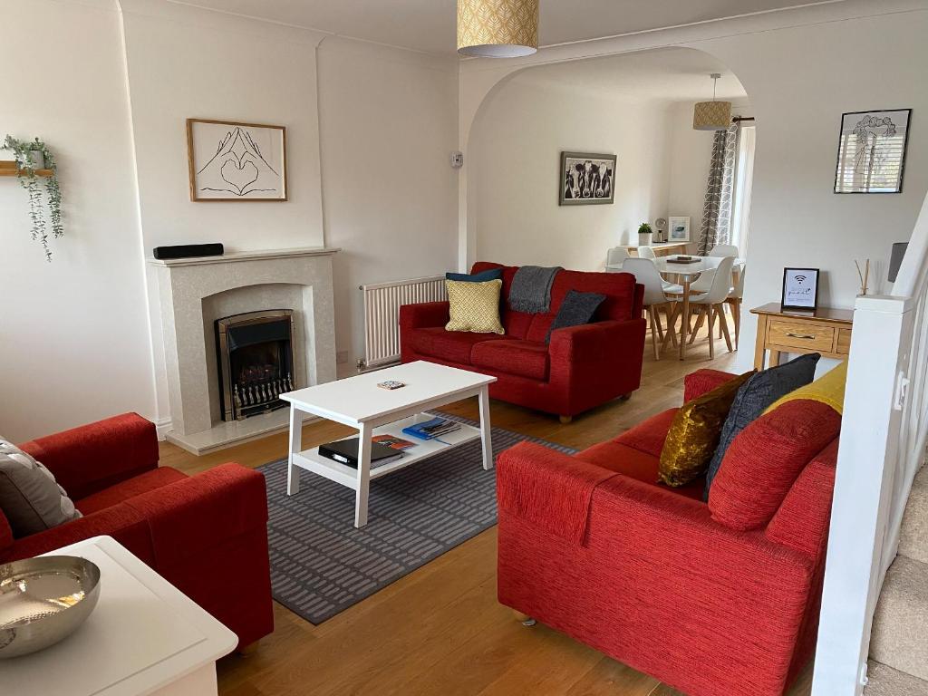 a living room with red chairs and a fireplace at Bayeux Cottage in East Budleigh