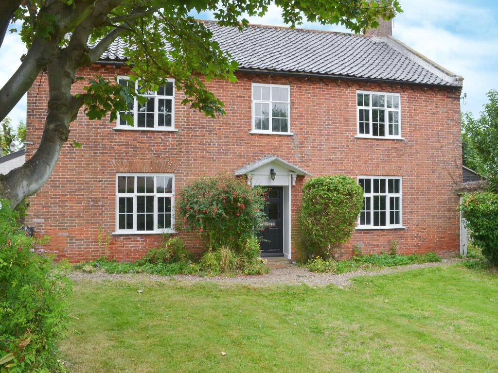 a red brick house with a tree in front of it at The Officers House in Bacton