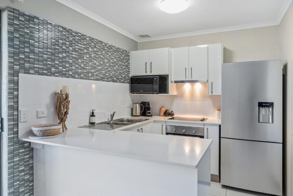a kitchen with white cabinets and a stainless steel refrigerator at Nautilus Noosa Holiday Resort in Noosaville