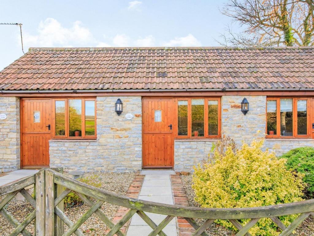 Cabaña de piedra con puertas de madera y valla de madera en Mendip View, en Wookey