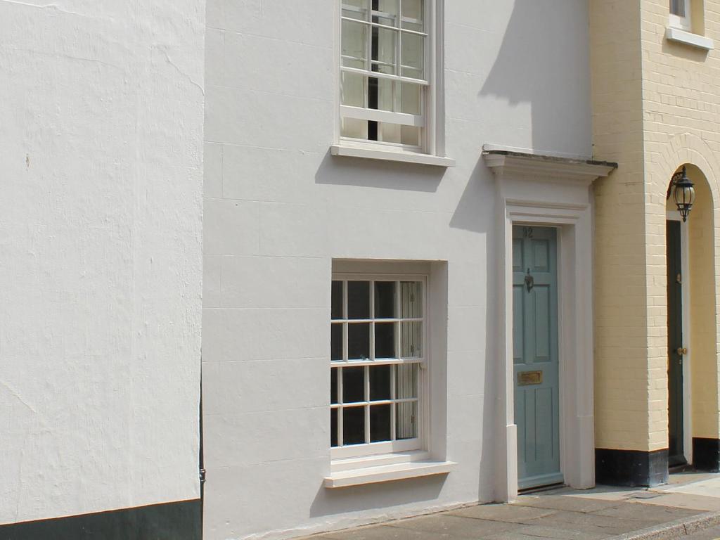 a white building with a blue door and windows at Anchor Cottage in Deal