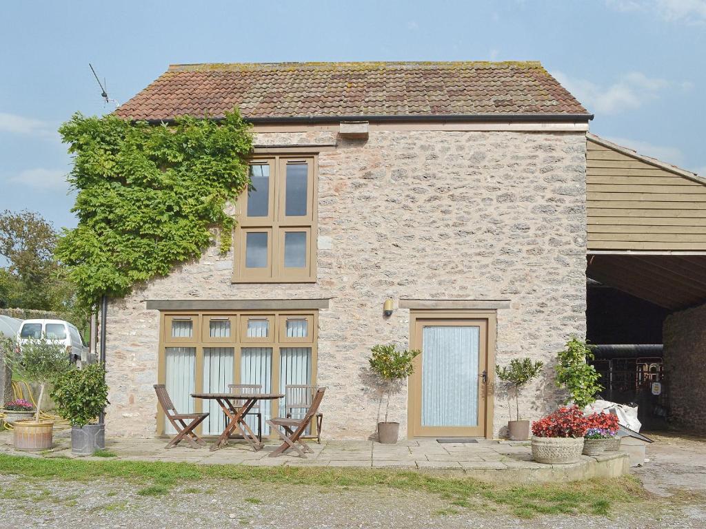 a house with a table and chairs in front of it at The Threshing Barn in Westbury-sub-Mendip