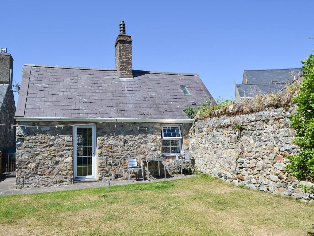 an old stone house with a stone wall at Bodwi Bach in Llanengan