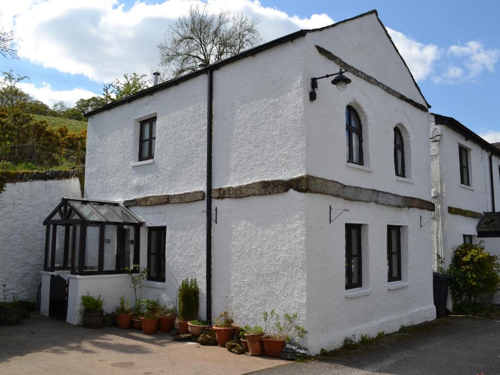 an old white house with black windows and plants at River View Cottage in Staveley