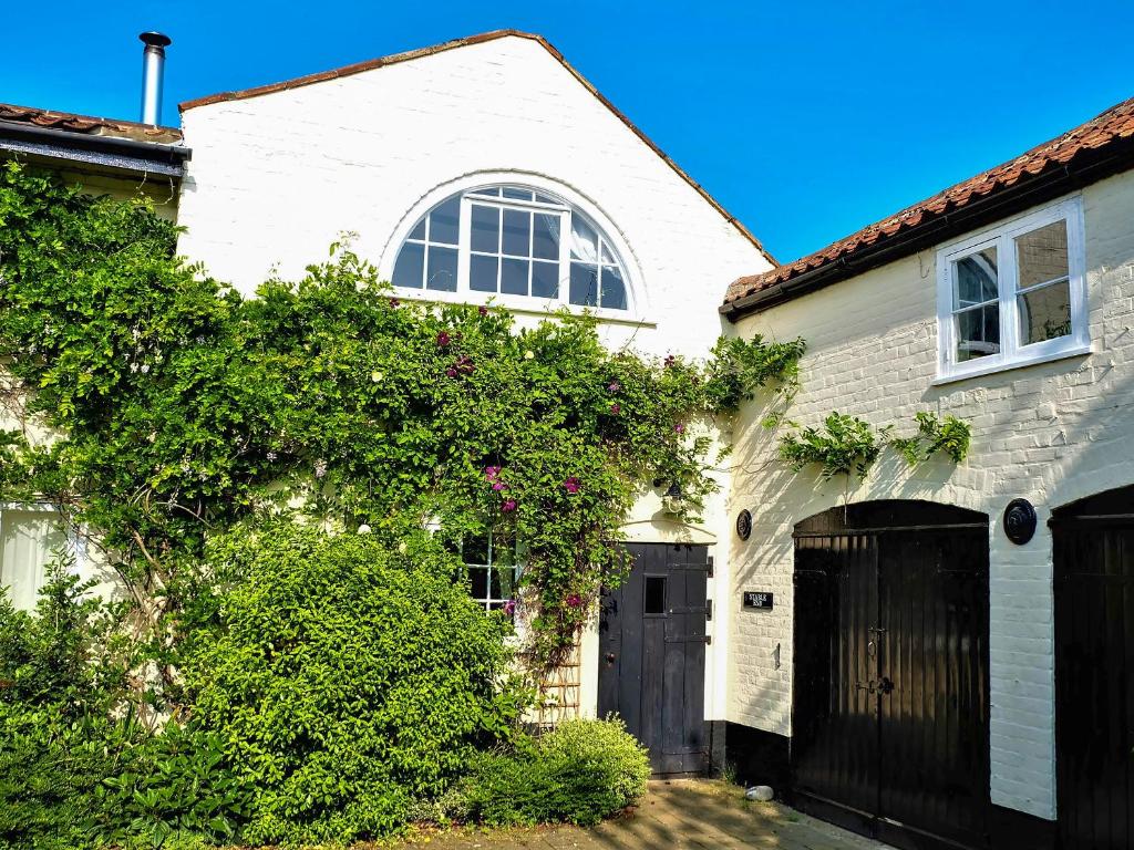 uma casa branca com uma porta preta em Stable End em Halesworth