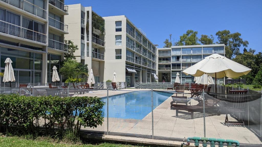 a swimming pool with an umbrella and chairs and a building at Concord Pilar Aparts in Pilar