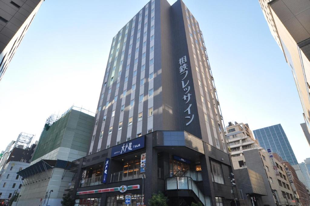 a tall building in the middle of a city at Sotetsu Fresa Inn Shimbashi Hibiyaguchi in Tokyo