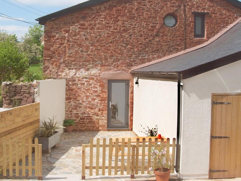 a barn conversion with a wooden fence in front of it at Dandelion Cottage - 28151 in Totnes