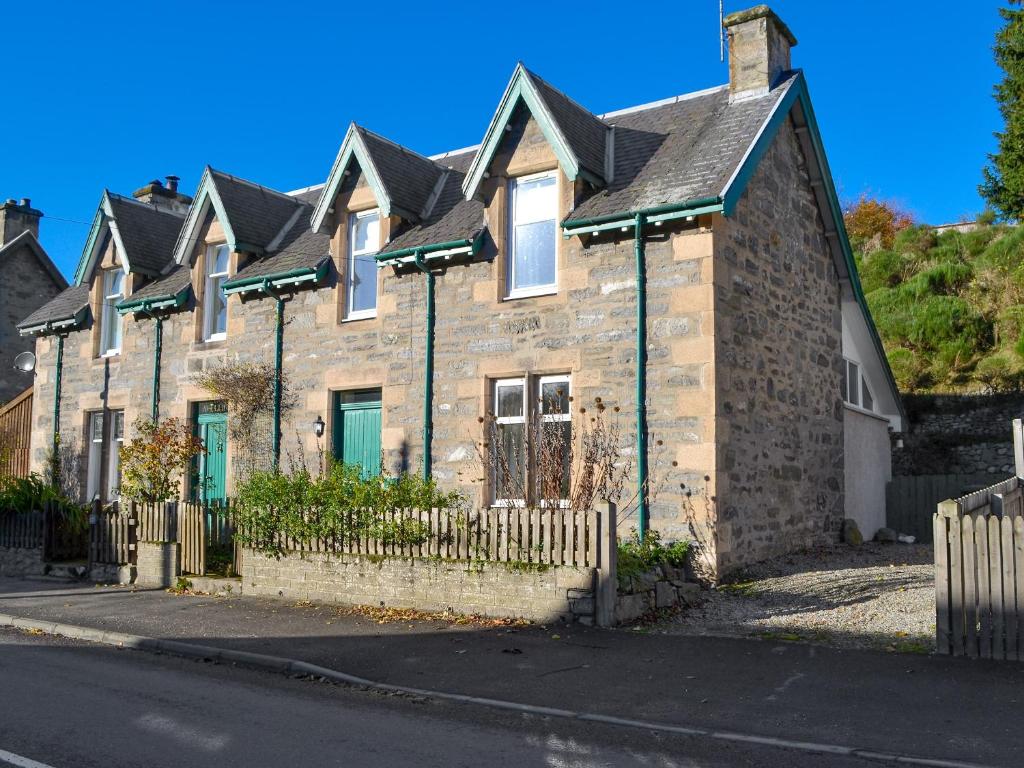 ein Backsteinhaus mit einem Zaun an einer Straße in der Unterkunft Langside in Kingussie