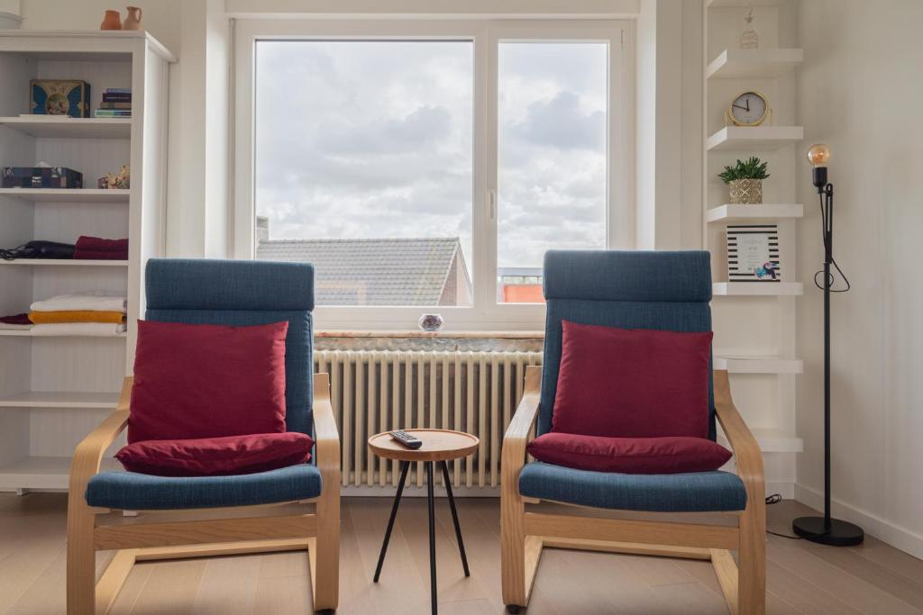 twee stoelen met rode kussens voor een raam bij Gasthuis 20 verdiep 2 in Kuurne