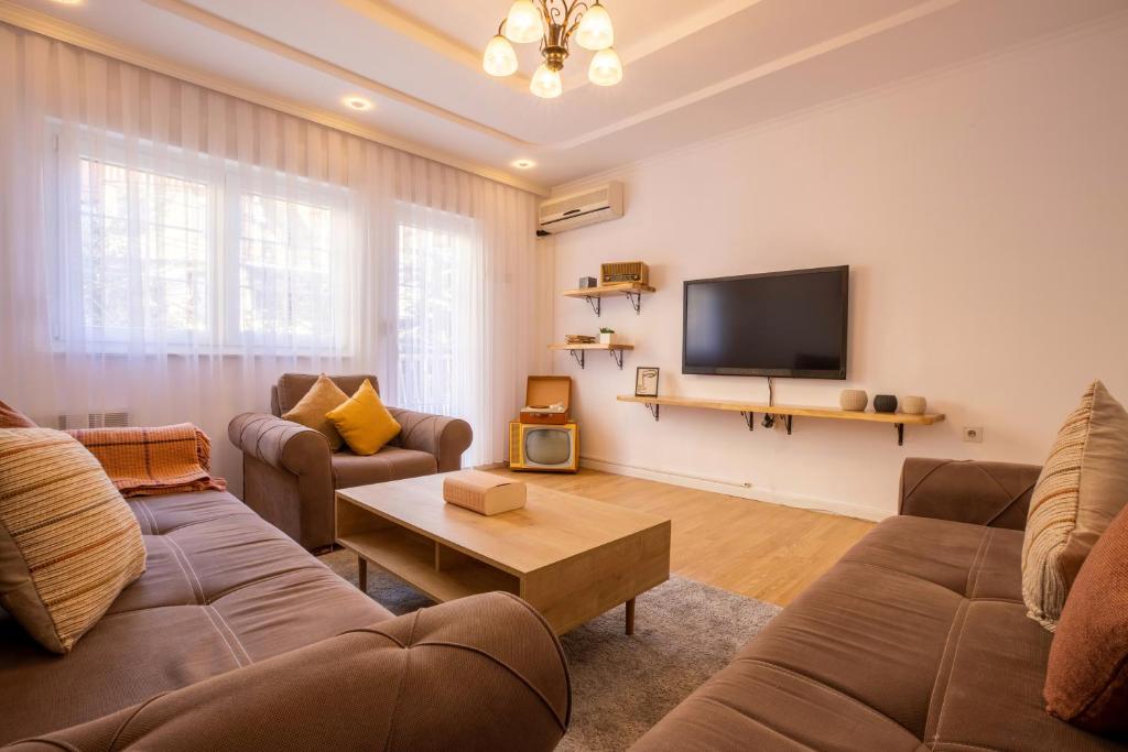 een woonkamer met 2 banken en een flatscreen-tv bij City Block Apartment in Pristina