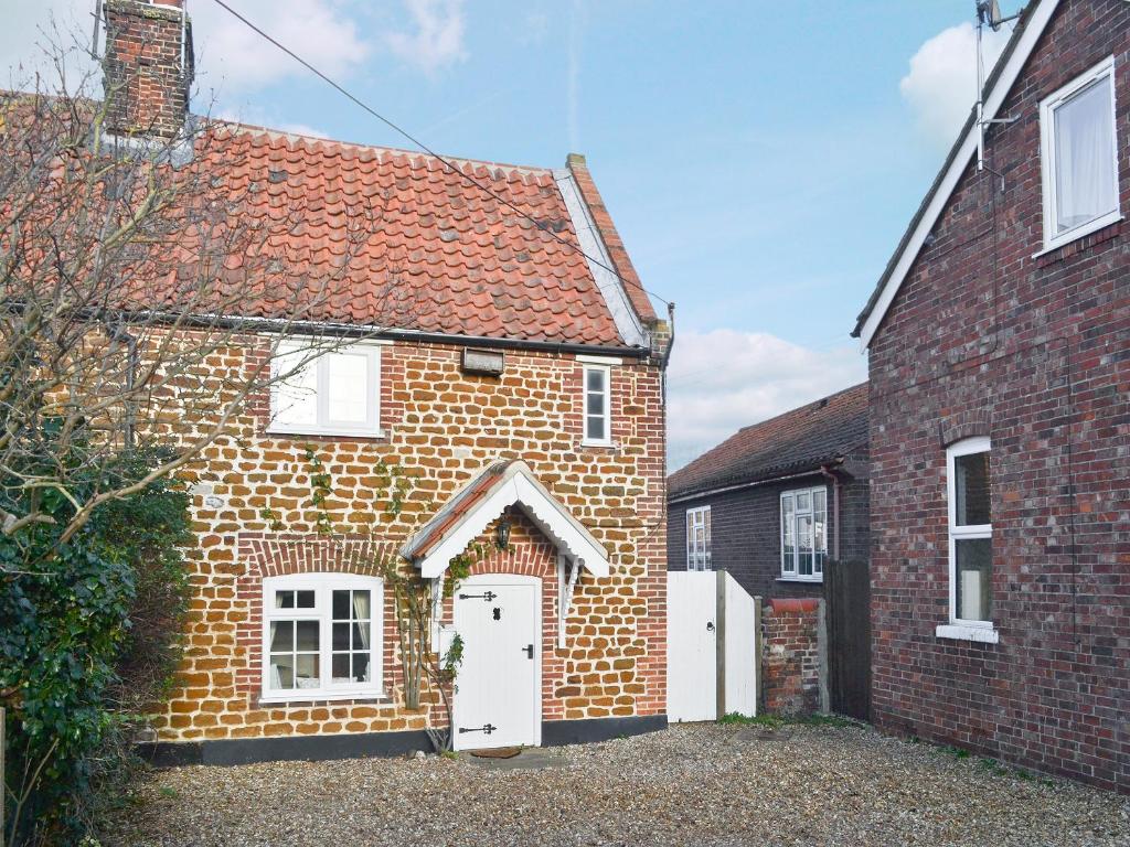 an old brick house with a white door at Sweet Pea Cottage in Heacham