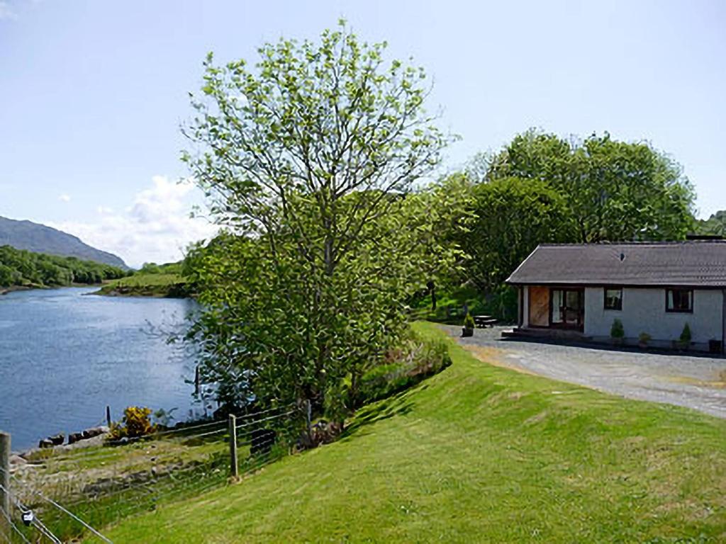 a house on the side of a river next to a building at The Narrows in Poolewe