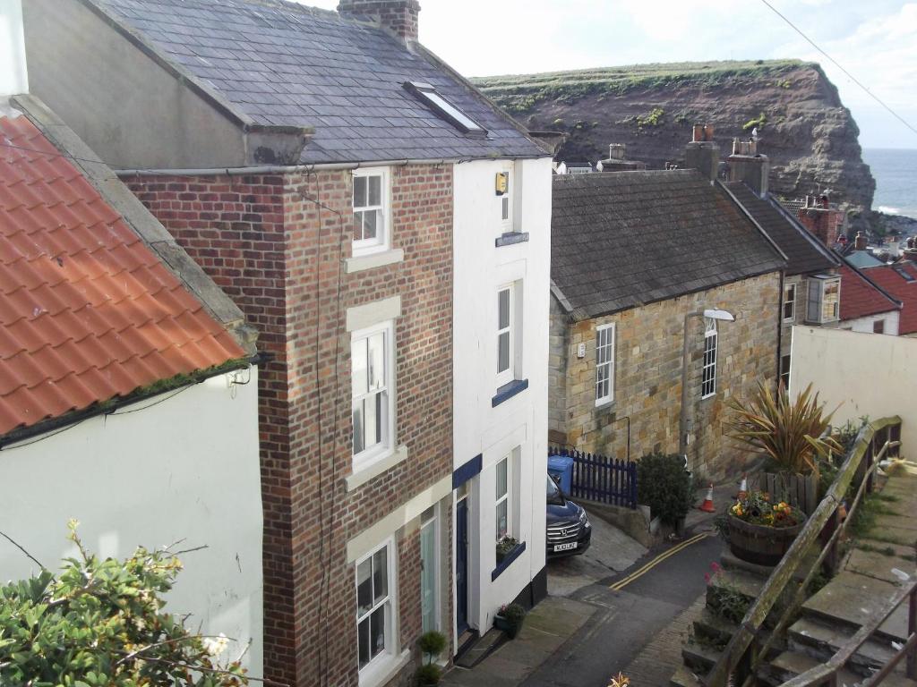 a group of houses with cliffs in the background at Holme Crest in Staithes