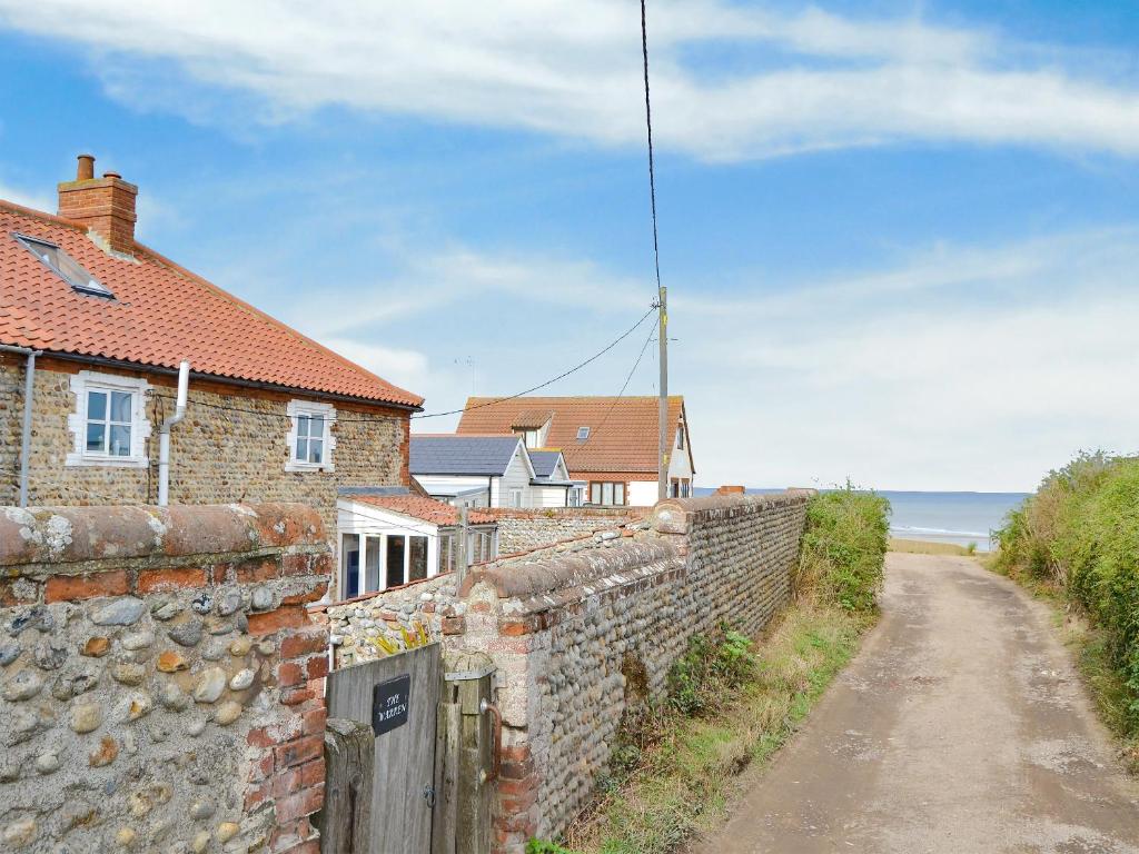 a brick wall and houses on a dirt road at The Warren in Bacton