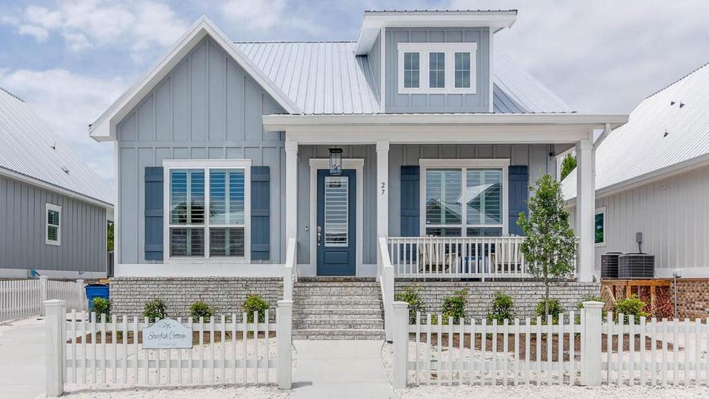 a house with a blue door and a white fence at Starfish Cottage in Gulf Shores