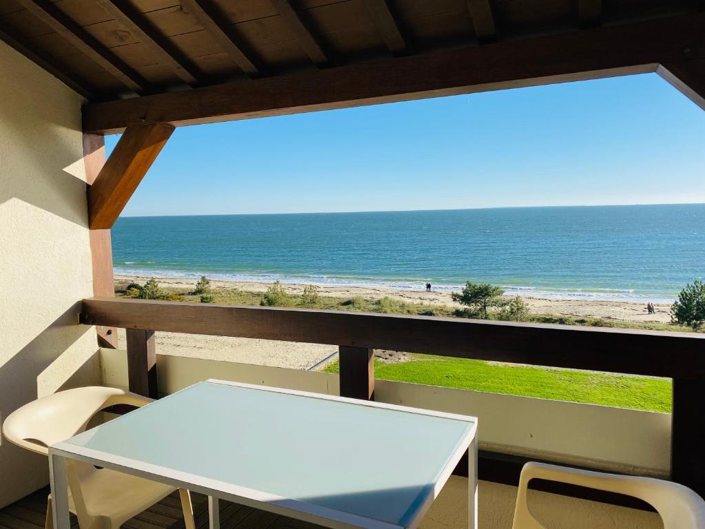 un tavolo e sedie su un balcone con vista sulla spiaggia di BRITANNIA - Studio tout équipé, Vue mer - U95 a Carnac
