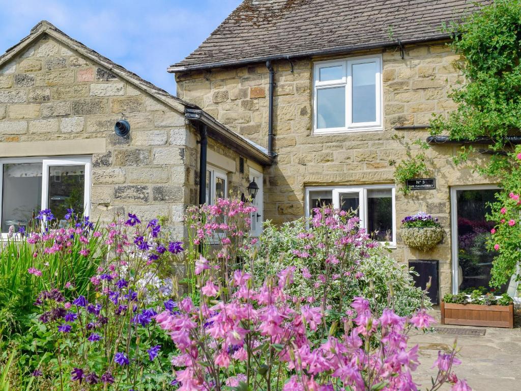 a stone house with flowers in front of it at The Causeway in Eyam
