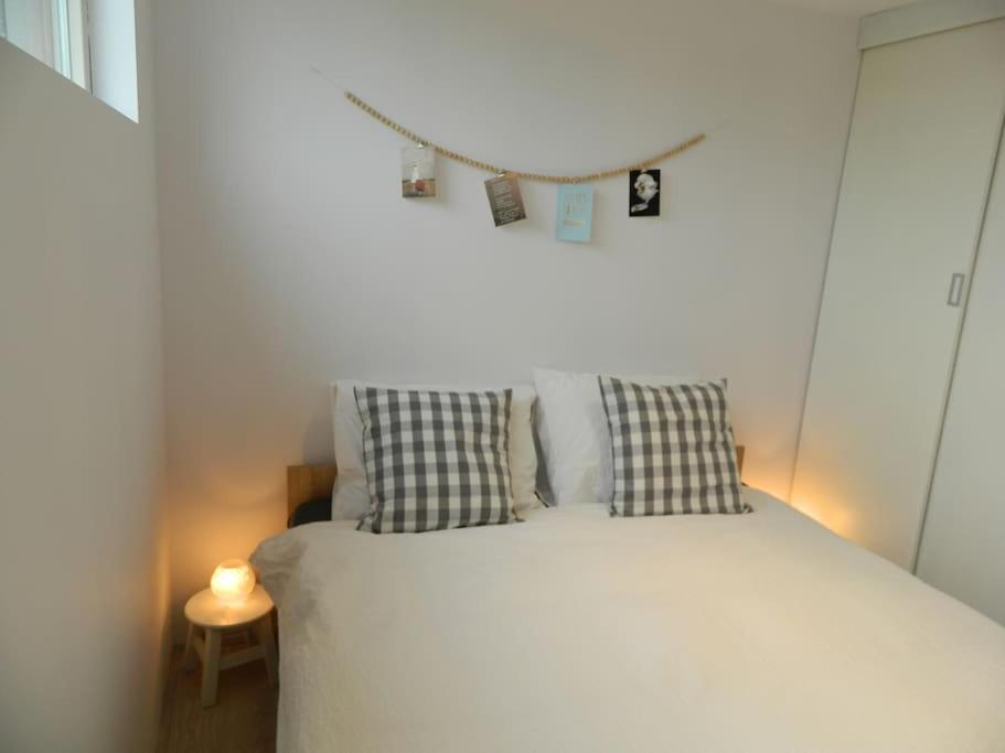 a bedroom with a white bed with two pillows at Modern en sfeervol appartement aan zee met airco in Zoutelande