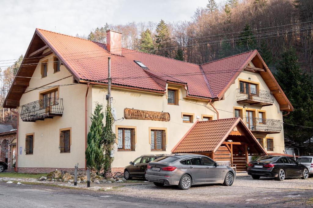 a building with cars parked in front of it at Penzión DolinkaGápel in Valaská Belá