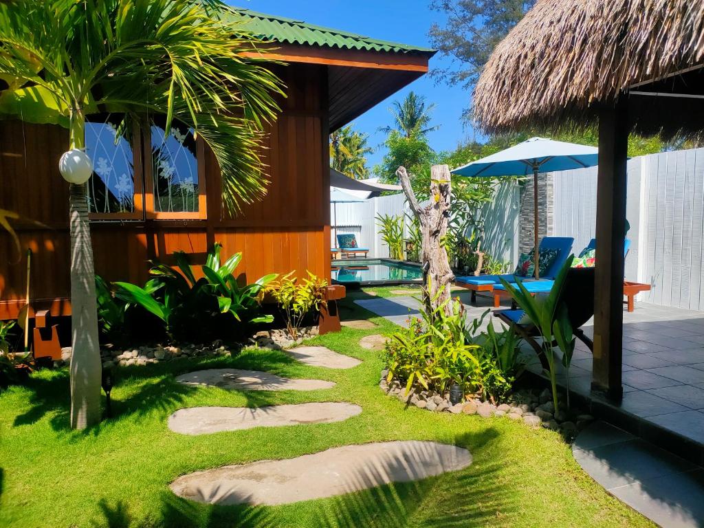 a garden with a resort with a swimming pool at Little Lodge in Gili Trawangan