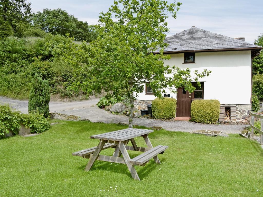 een picknicktafel in het gras voor een huis bij Honeysuckle Cottage - 29938 in Holcombe Burnell