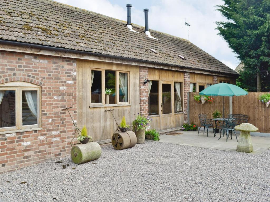 a brick house with an umbrella and a patio at The Chaff House in Arlingham