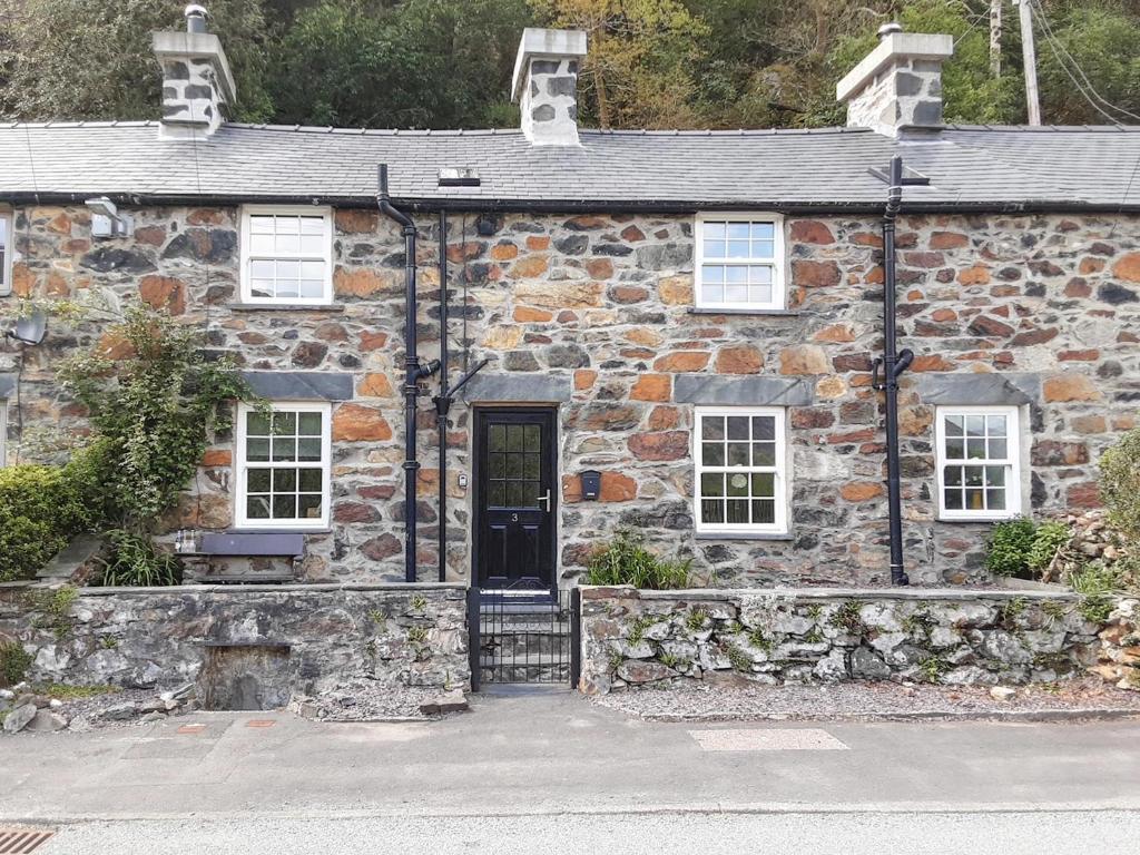 an old stone house with a black door at Old Tan Rhiw in Beddgelert