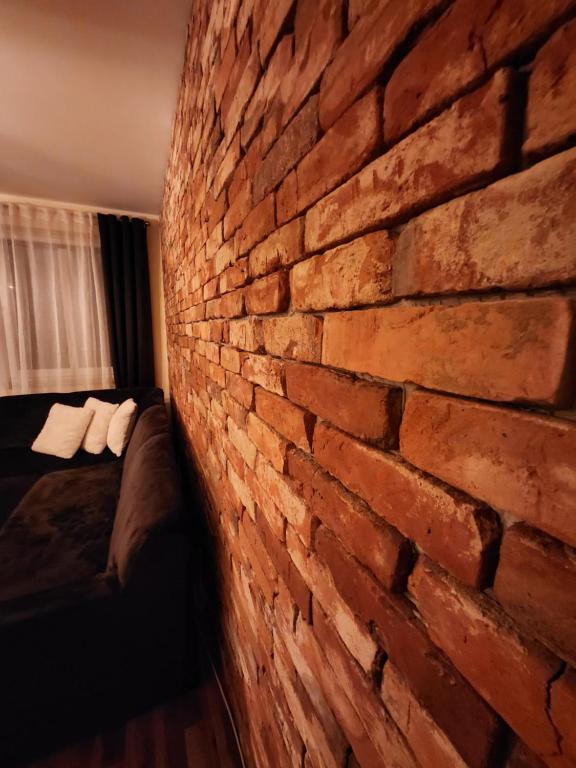 pared de ladrillo en una habitación con sofá en Apartament P&P Prestige II en Inowrocław