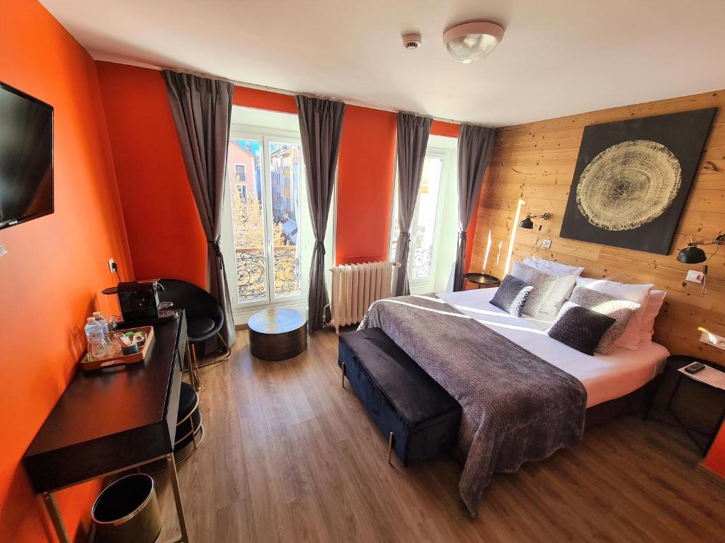 a bedroom with orange walls and a bed and a television at Le Grand Hotel in Barcelonnette